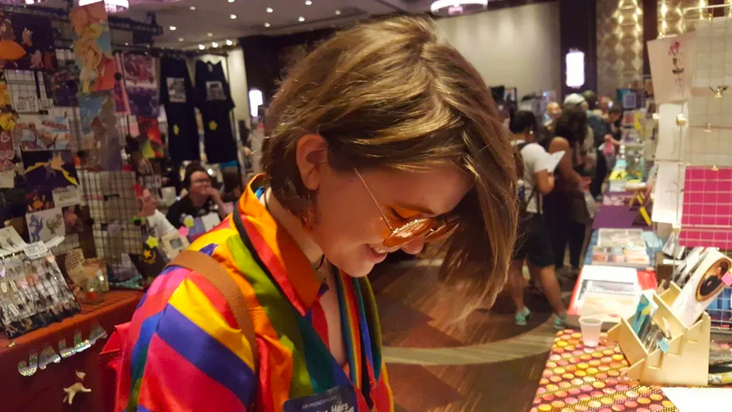 A young person stopping to interact at a Flame Con artist table.