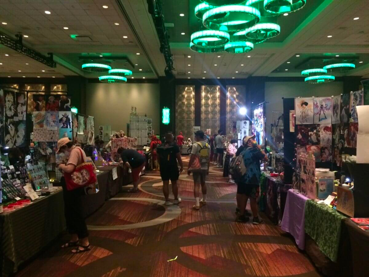 People walking down a vendor-lined aisle at Flame Con.