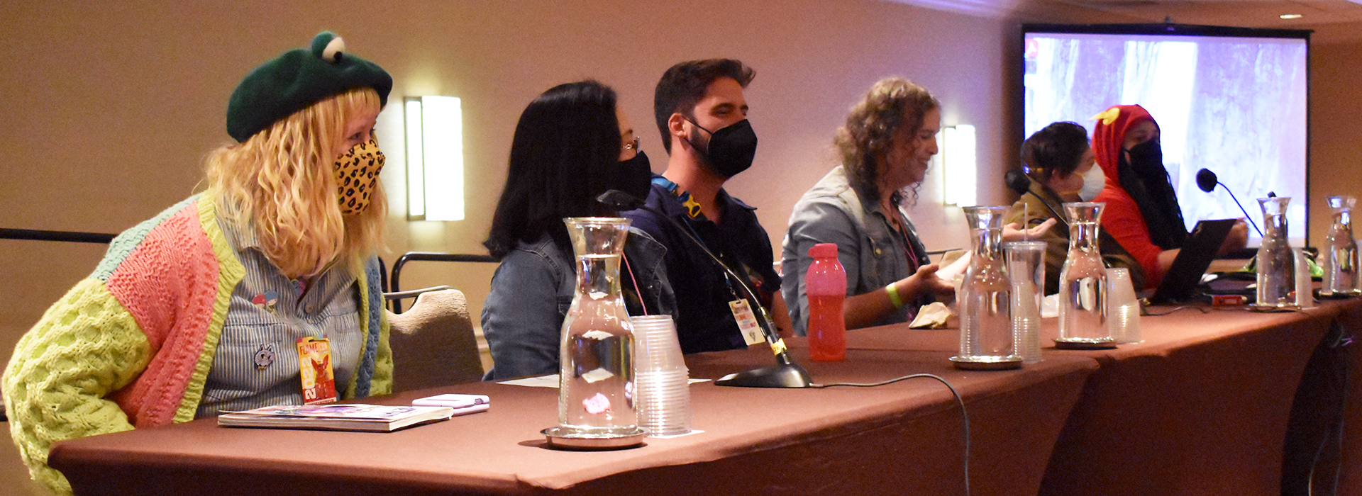 A programming panel of six individuals in front of a projection screen. 